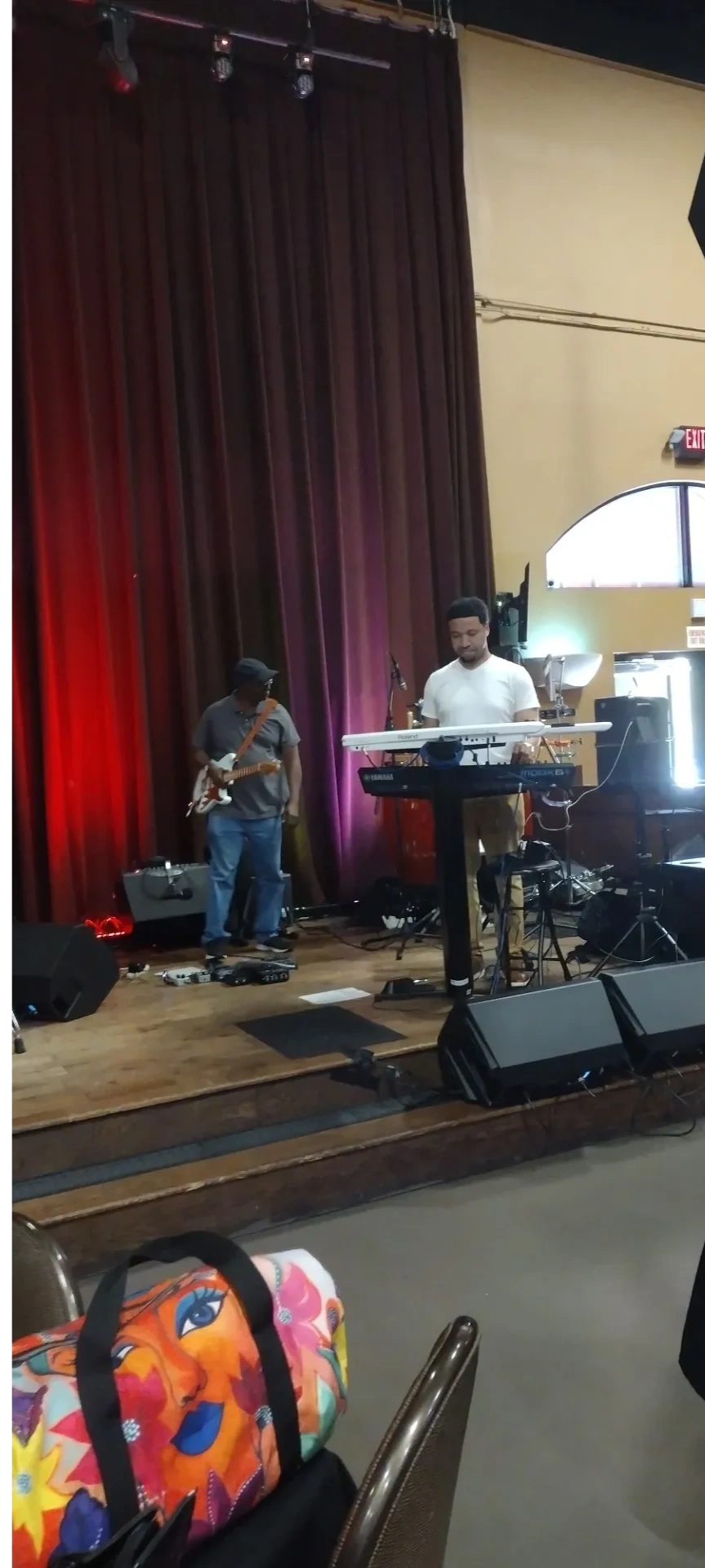 Band members performing on wooden stage with burgundy curtains