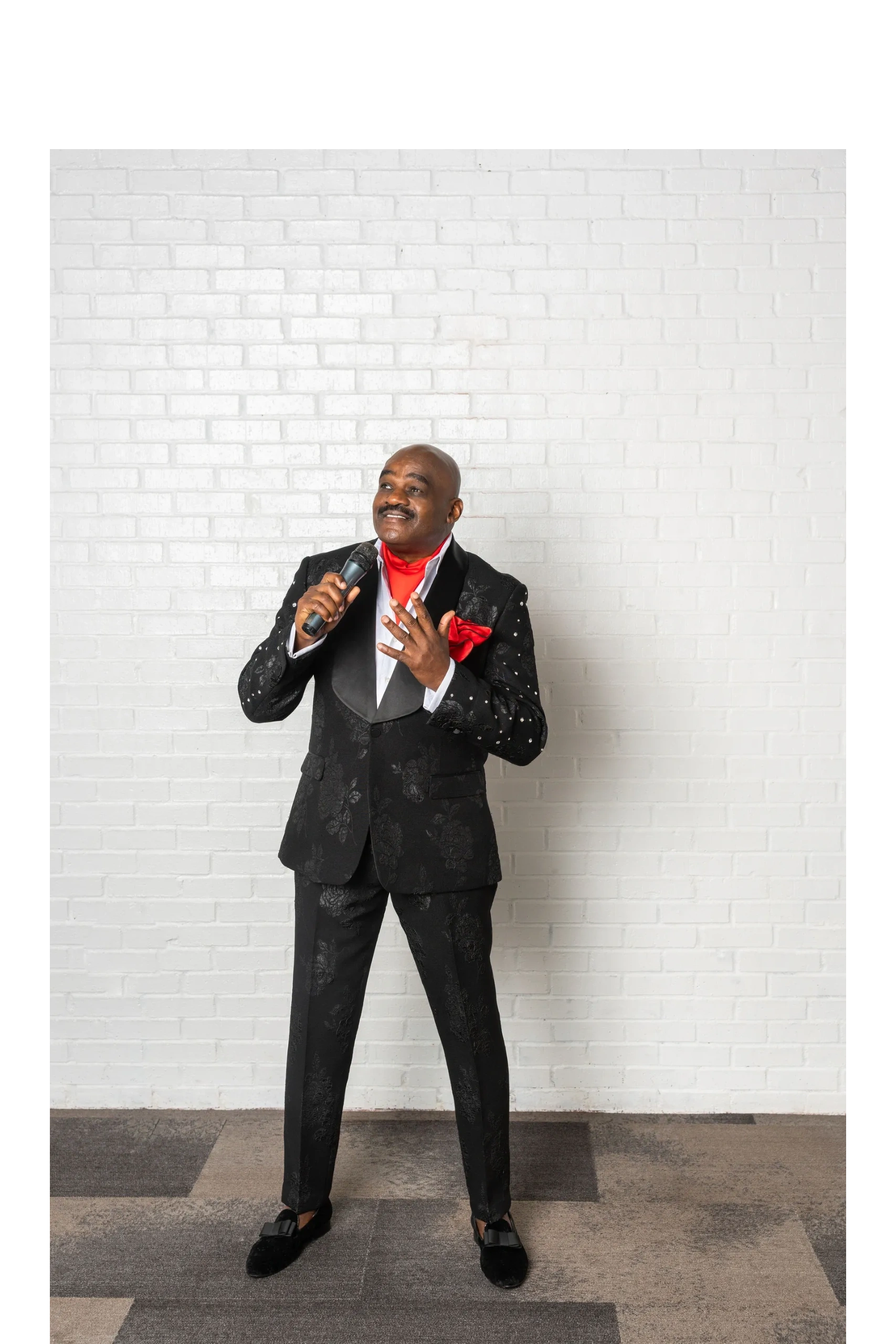 Julius Williams in black sequined blazer holding microphone