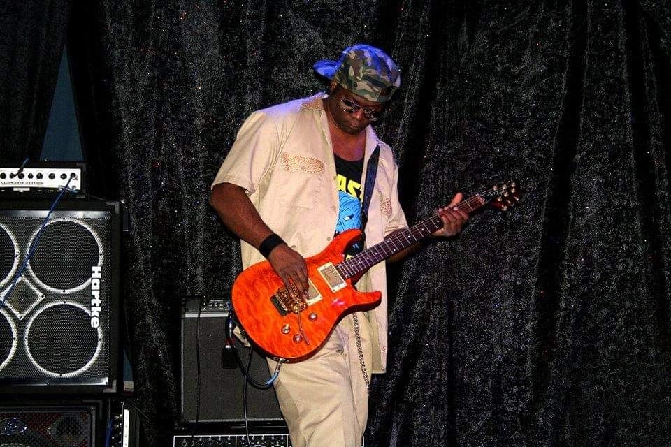 Juan Whiz Mitchell playing red electric guitar on stage