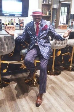 Julius Williams in polka dot blazer seated in tufted chair