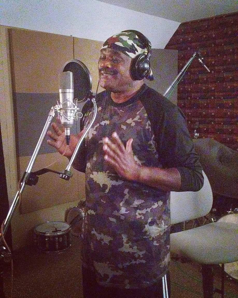 Julius Williams recording in studio wearing headphones at microphone